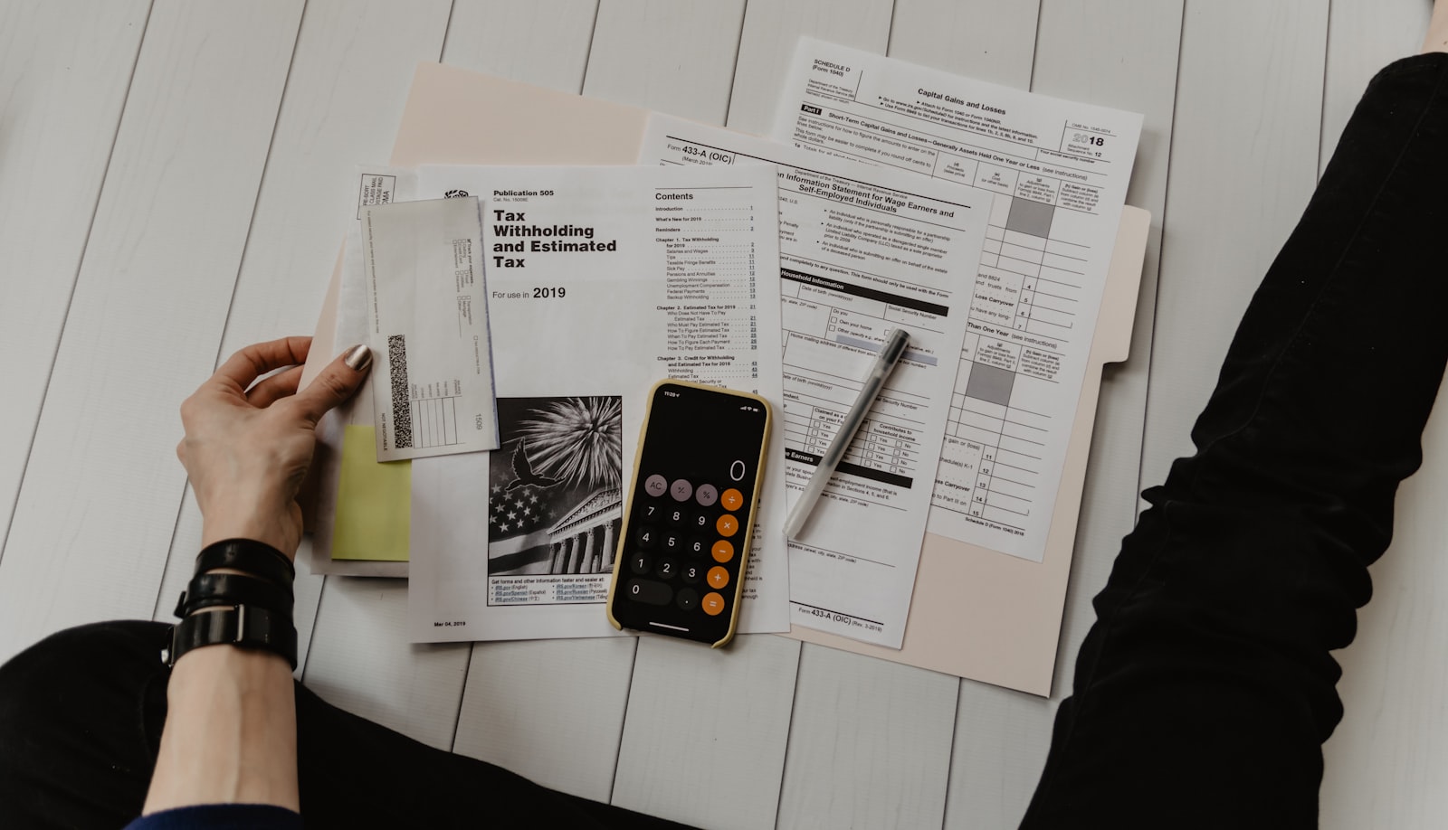 Laskin, kynä ja paperit verolaskelman äärellä